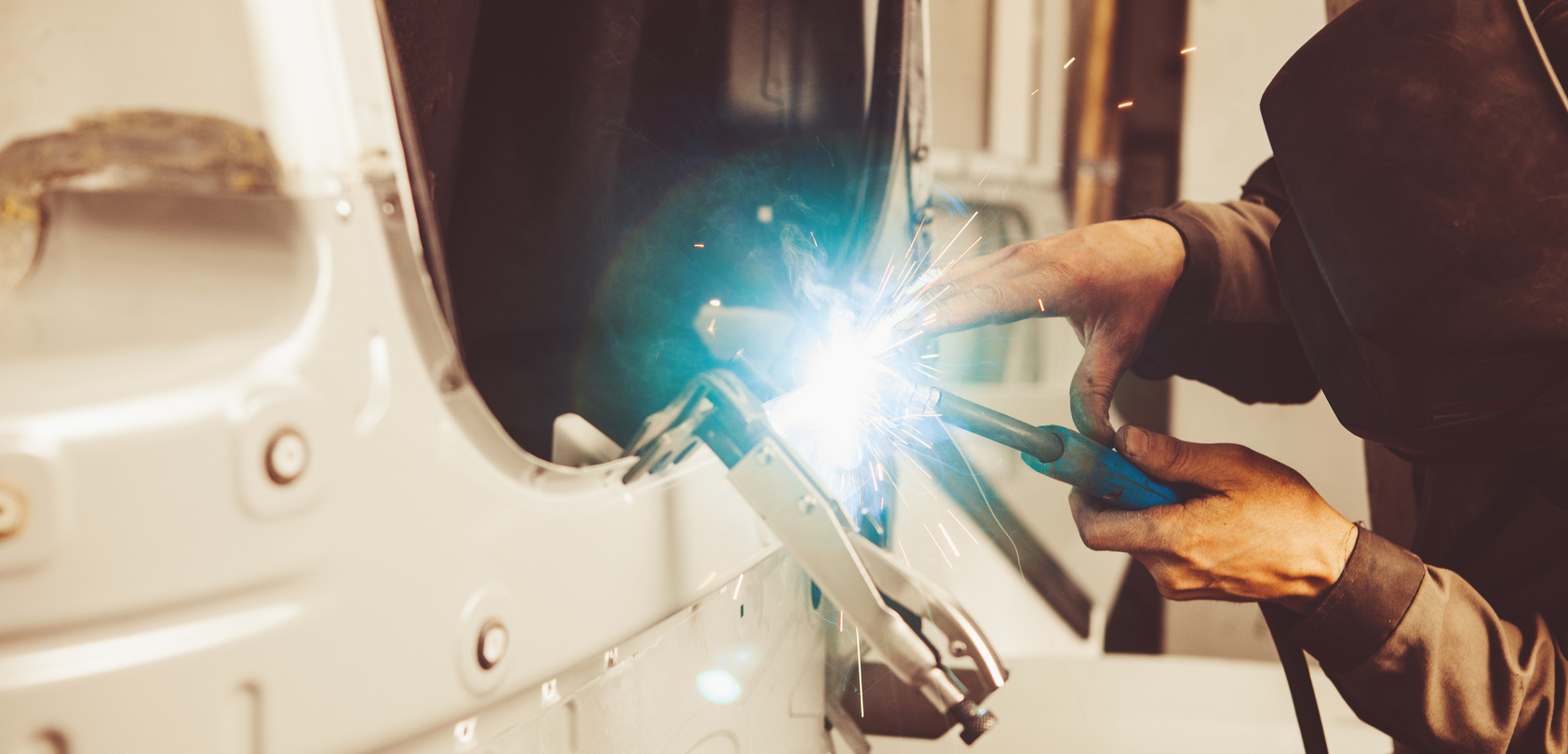 Industrial welder welds back bodywork of car. Weld of vehicle.